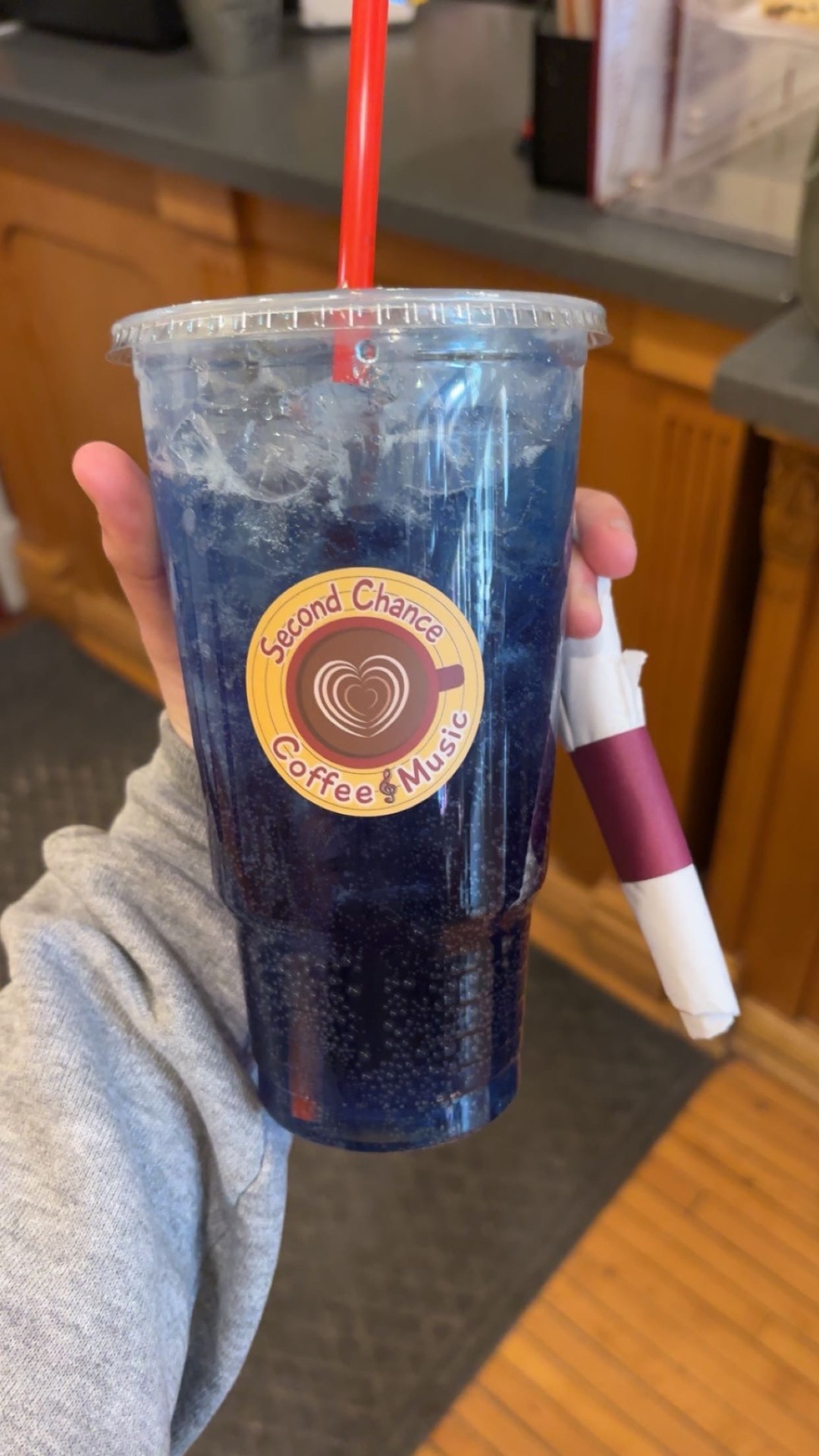 A bright blue Lotus spritzer in a Second Chance Coffee & Music cup.